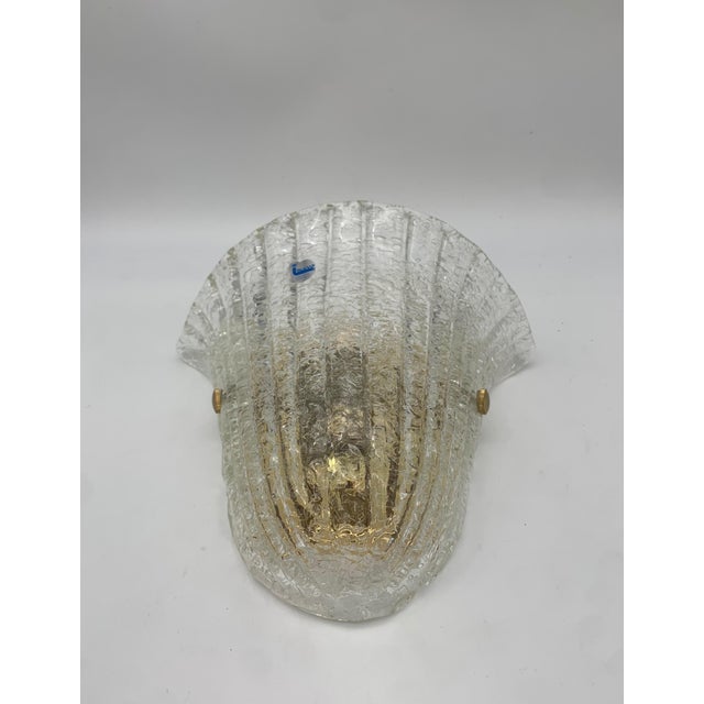 Italamp wall lamp with a clear glass diffuser shaped like a half-bowl, featuring a relief pattern that creates a play of...