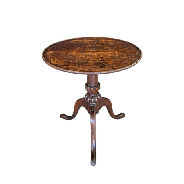 A fine Georgian tilt-top table in oak, circa 1780; featuring a pedestal resting upon three splayed Queen Anne style legs...