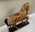 A large carved and painted wooden carousel style horse in a standing pose on a black base with vibrant polychrome...