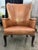 French Country wingback armchair, hand-crafted in the 20th Century. Beautifully tailored leather upholstery with brass...