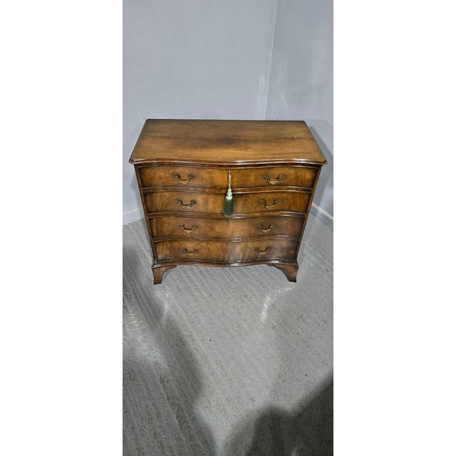 A very fine oak lined Georgian style serpentine mahogany chest of four drawers by Maples, brass swan necked handles,...