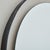 A vintage round wall mirror featuring a minimalistic black metal frame. Patinated brass notches secure the frame to the...