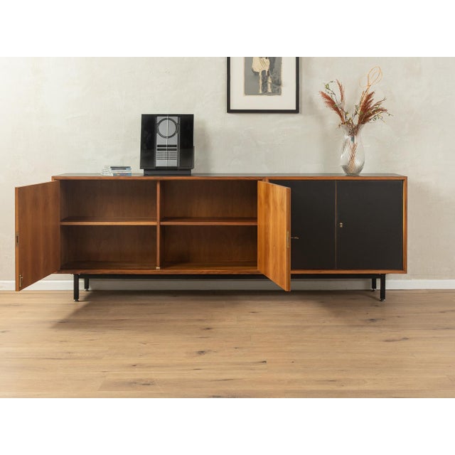 Classic sideboard from the 1960s. High-quality walnut veneer body with four doors, three shelves, and new black square...