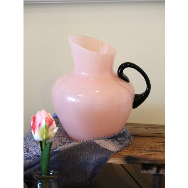 This is a stunning pink opaline glass pitcher with an applied black glass handle. Opaline glass dates back to the 16th...