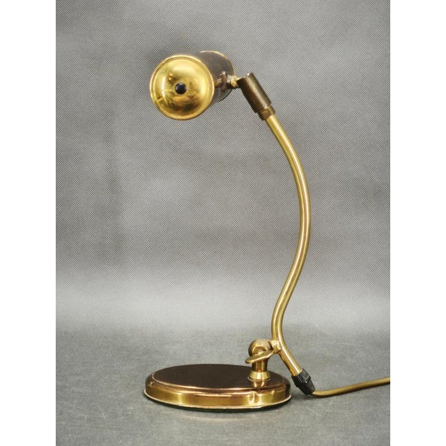 An elegant and highly functional adjustable german table lamp from the 1960s, executed primarily in brass with metal and...