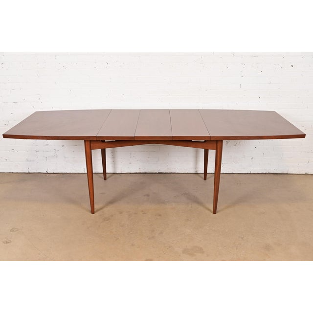 An exceptional Mid-Century Modern walnut boat-shaped extension dining table In the manner of Gio Ponti USA, 1960s...