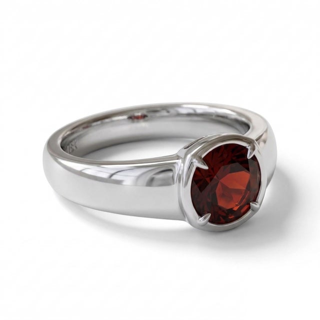 This elegant ring features a striking Garnet gemstone, admired for its deep red hue and rich, fiery brilliance. Garnet is...