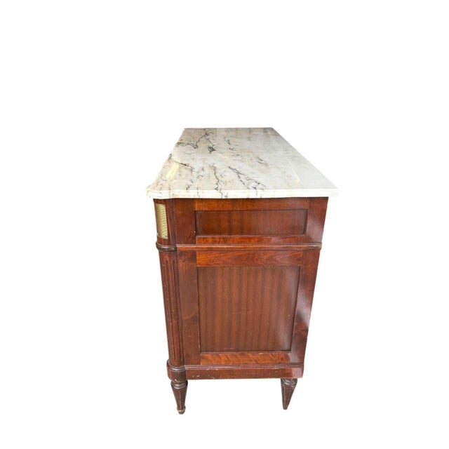 This stately French Mid 20th Century Empire-style commode features a richly grained solid mahogany case topped with a...