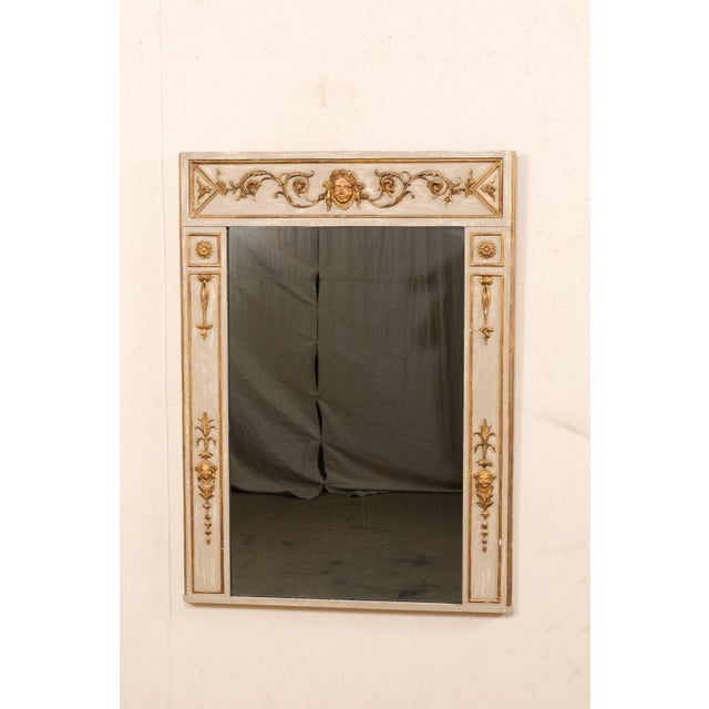 An Italian Neoclassical carved and gilt wood frame mirror from the 19th century. This antique mirror from Italy is...