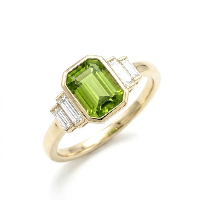 Refined and architectural, this stunning ring features a vibrant 7x5mm emerald-cut peridot, secured in a sleek, protective...