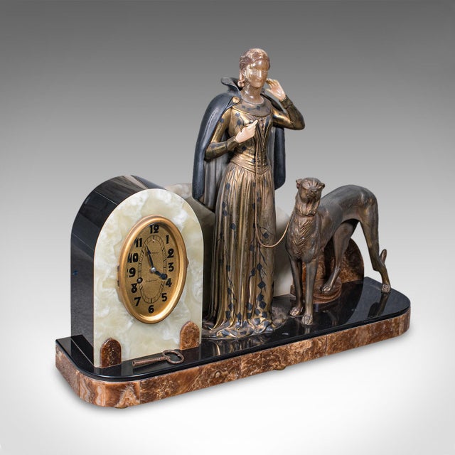 This is a large vintage figural mantle clock. A French, onyx and spelter timepiece with matched garnitures, dating to the...