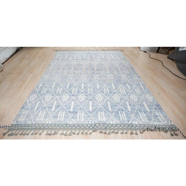 This blue wool rug features a hand knotted pile construction in the style of a traditional Berber carpet. Originating from...