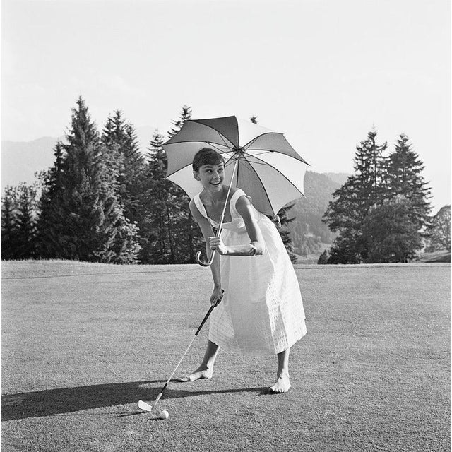 Golfing Hepburn 1955: Belgian-born actor Audrey Hepburn (1929 - 1993), barefoot and wearing a summer dress, playing golf...