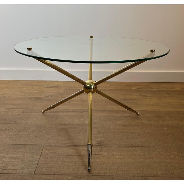 This round tripod coffee table with a pleasing design is made of brass with a glass top. It is a French work. Circa 1970