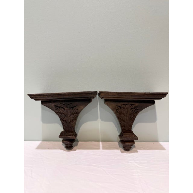 Elegant and timeless, this pair of vintage hand-carved wooden wall shelves features intricate acanthus leaf motifs and...