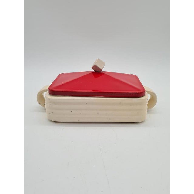An original butter dish with an exceptionally elegant, geometric form. The body is made of cream-glazed ceramic, while the...