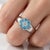 This charming and elegant ring features a delicate floral cluster design, highlighted by vibrant Blue Topaz gemstones...