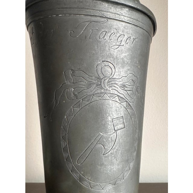 Hand etched phrase “das amt der traeger ihre kanne” with an axe and ribbon in the center. On the handle there are stamps...