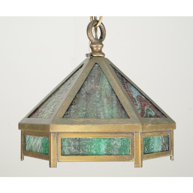 Arts & Crafts style pendant light featuring marbled green slag panels and brass framing. The chain is made of steel. This...