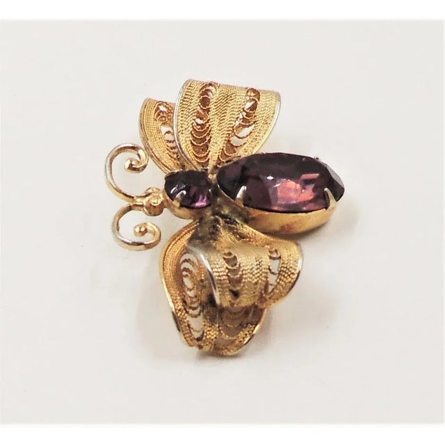 This is part of Chairish’s Costume Jewelry assortment. Late 1950s goldtone round and oval faux-topaz fly with filigree...