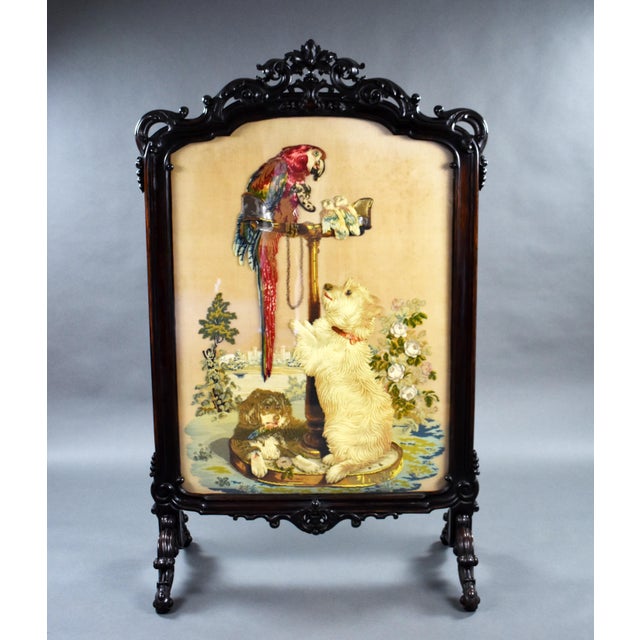 A fine and rare large victorian rosewood screen, having an ornately carved top, above embroidery, depicting a dog jumping...