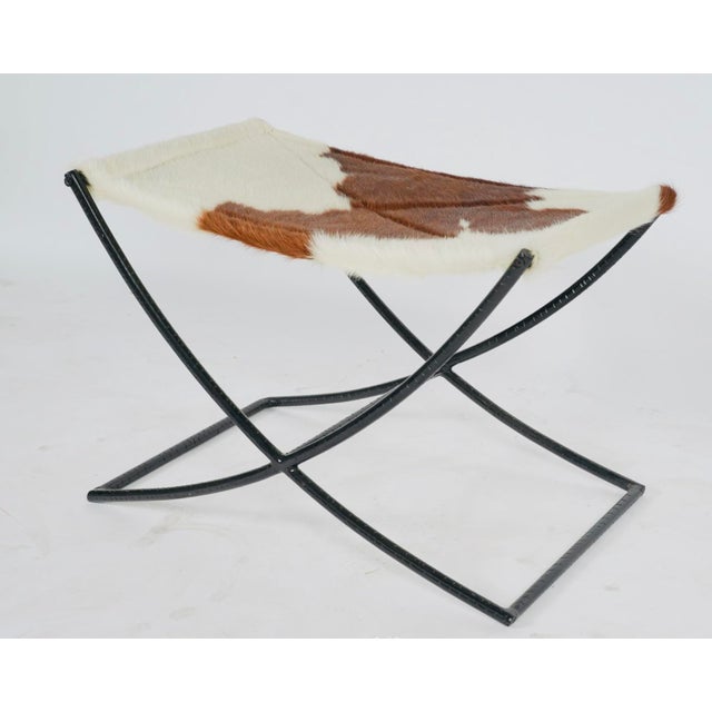 A handsome accent stool featuring a brown-and-white hair-on-hide sling seat over a sculptural black metal X-base. The...