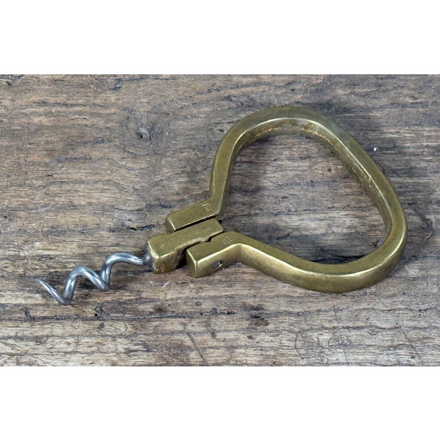 Vintage brass ring-style corkscrew with integrated finger loop handle and steel worm, designed for compact carry and easy...