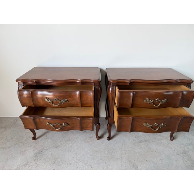 Elegant vintage Louis XV style French Provincial nightstands featuring beautifully shaped bombe cases, serpentine drawer...