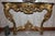 A Louis XV style wall console with a richly worked gilt frame beneath a serpentine dark green marble top veined in white....