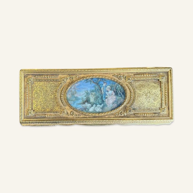 This late Victorian gilt brass box features a porcelain oval inset in the hinged lid. The hand painted vignette is signed....