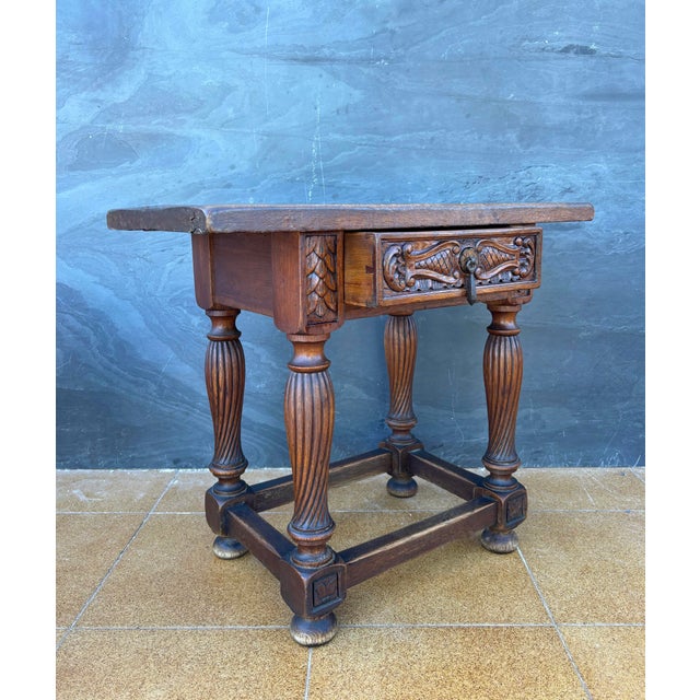 Spanish Renaissance Revival side table crafted in solid oak, Early-20th century. The table features a richly carved drawer...