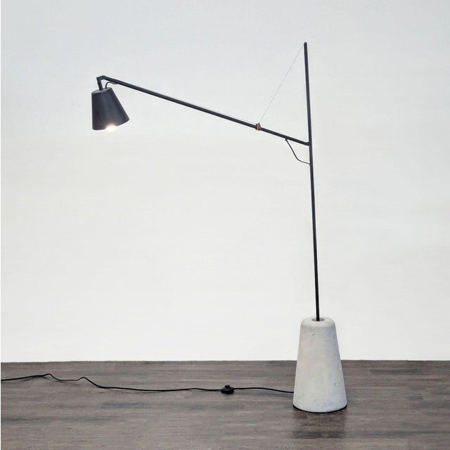 This EQ3 floor lamp features a sleek black metal design and a sturdy concrete base. Perfect for modern spaces, it has an...