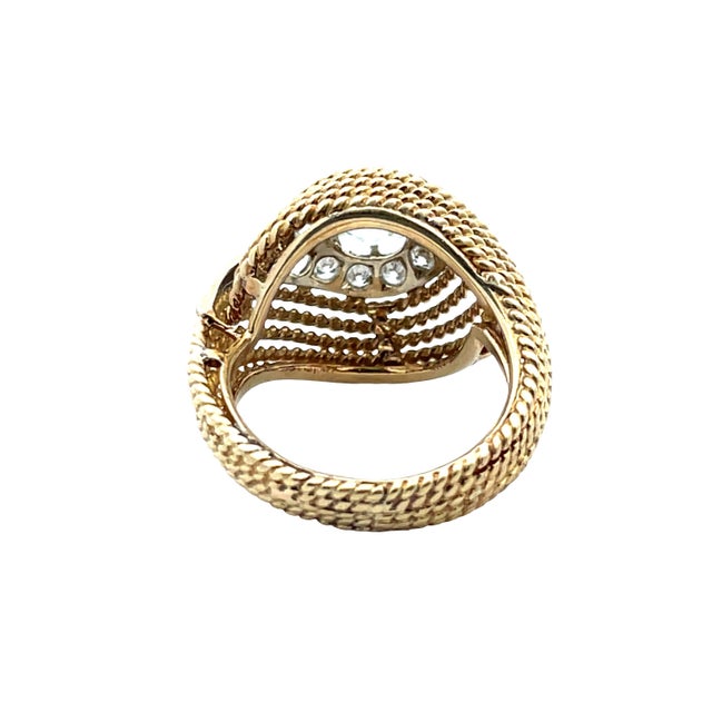 An elegant vintage swirl ring crafted in 18K yellow and white gold, featuring a flowing, sculptural design. The ring...