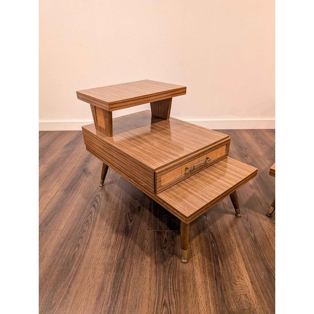 Great little pair of mid century modern step tables. They feature a three tiered design with laminate tops, a single...
