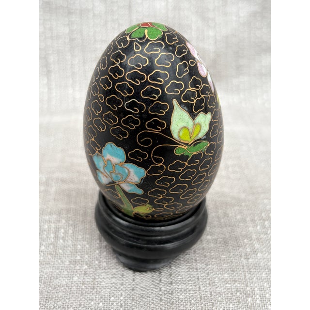 Vintage black floral Chinoiserie cloisonne egg with a separate round wooden stand. No marks. Egg measures 2 5/8" by 1 3/4"...