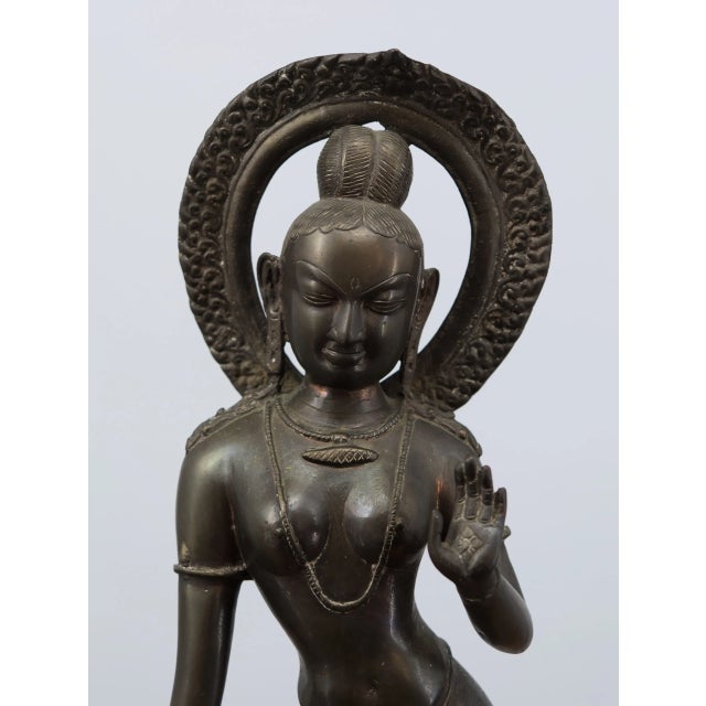 A distinctive bronze temple statue originating from India, made using the traditional casting technique. The figure is...