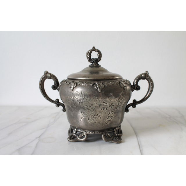 Antique quadruple-plate footed lidded sugar bowl, produced by E.G. Webster & Son. Features ornate, hand-chased or embossed...