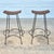 This is a stylish pair of midcentury modern bar height stools featuring handwoven natural rattan tops supported by sleek...
