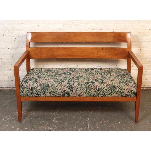 This modern loveseat is made of a strong wood frame with nice curved lines and a cushioned seat with bright floral pattern.