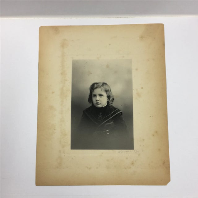 Original photographic print of a young boy in a velvet sailor suit. Paper has minor foxing and chipped corners. Signed...