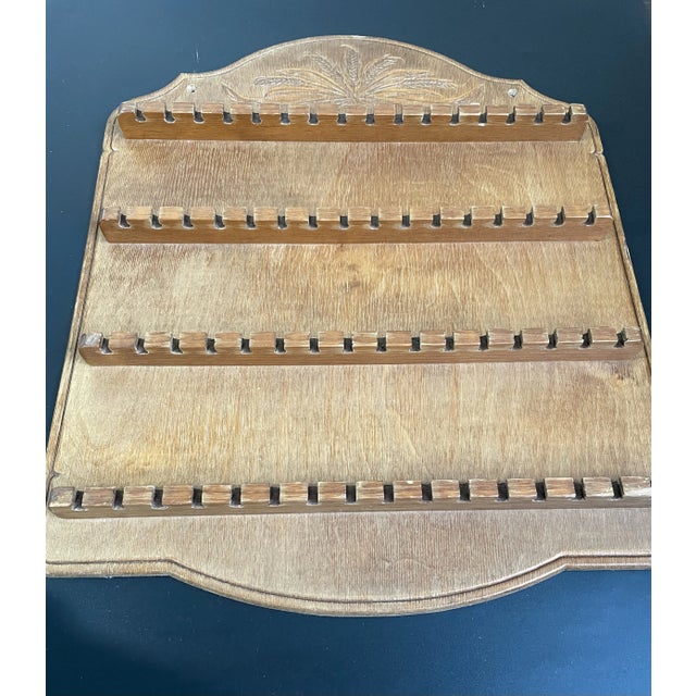 A vintage wooden rack designed to display 64 collectible spoons, featuring a carved decorative wheat motif at the top....