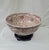 Large Chinese porcelain punch bowl featuring an intricate all-over floral and vine motif in a warm burnt orange and...