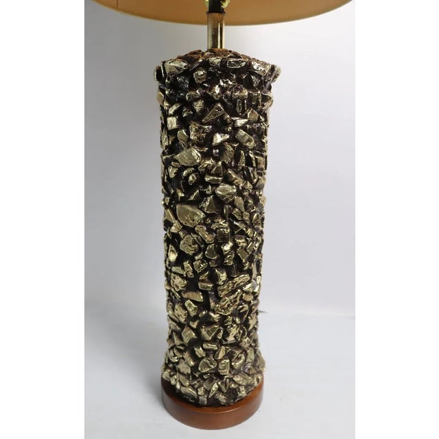 Chic ceramic table lamp having a cylindrical body with a black ground and textured gold nuggets embedded in the surface....