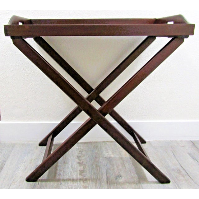 A handsome richly stained mahogany vintage Butler's Tray Table that sits on a folding stand, circa Mid 20th Century. This...