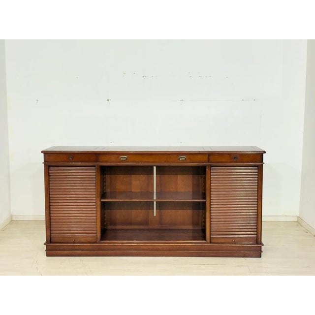 An elegant and high-quality office sideboard made of fine, dark-stained wood in the classic English colonial style. The...
