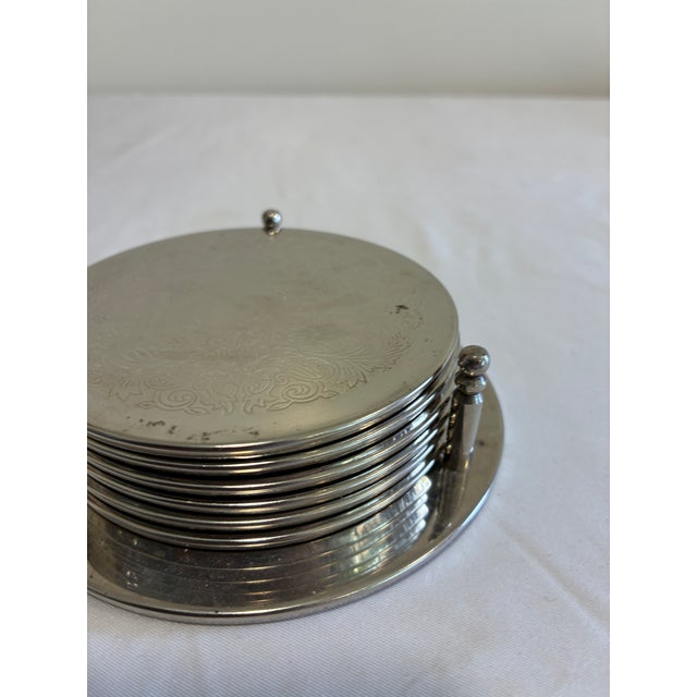 Beautiful vintage silver-toned coaster set with matching holder. Includes 6 round coasters with delicate floral and scroll...