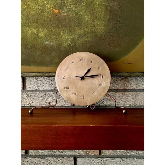 This vintage clock has an 8" brushed face with hand-hammered Roman numerals. Crafted from a mixture of metals, this...