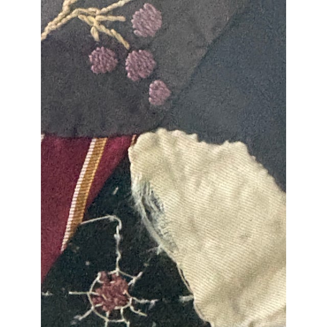 An antique Victorian-era crazy quilt block or fragment featuring asymmetrical, multi-textured fabrics such as silk,...