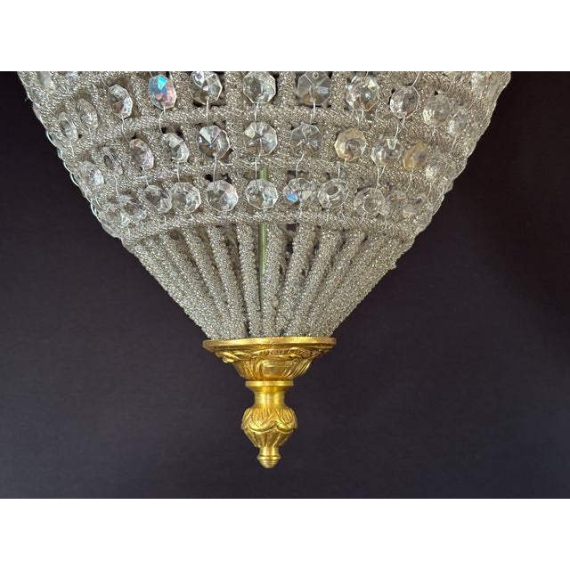 A refined 1980 French Louis XVI-style bronze and crystal lantern chandelier, made in Europe and designed with a warm gold...