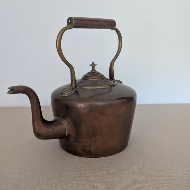 A handsome 19th-century English copper kettle with a beautifully aged surface, warm patina, arched handle, and elongated...